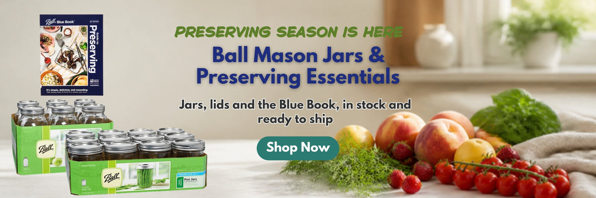 Ball Mason jars and preserving essentials: half gallon jars, pint jars and the Ball Blue Book on a kitchen bench